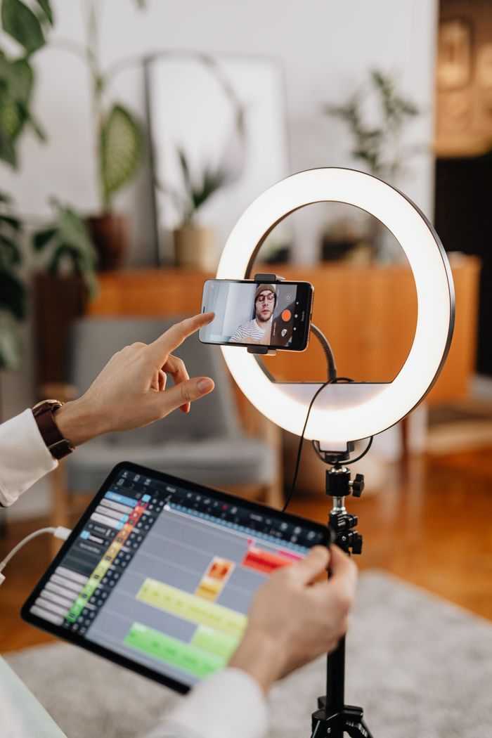 project-01-c A content creator uses a smartphone and ring light setup for vlogging indoors.